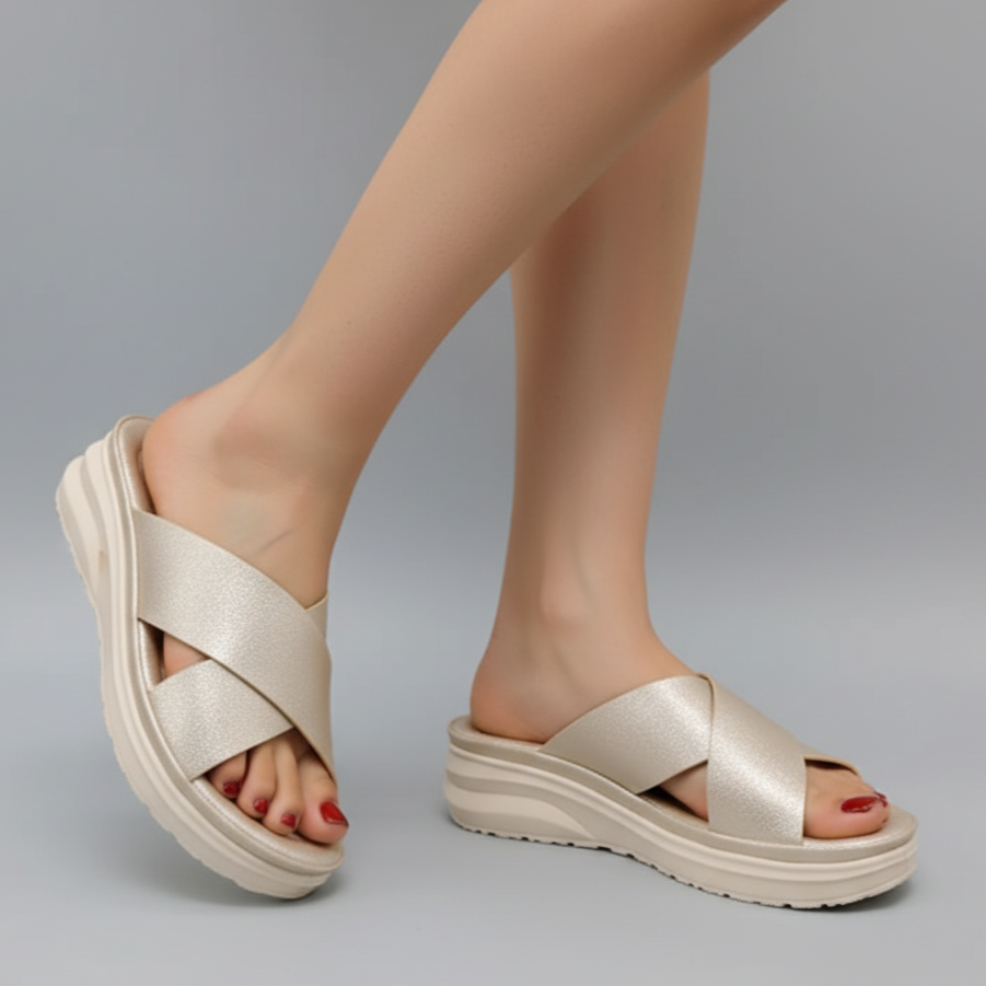 Beige sandals worn by a person on a gray background