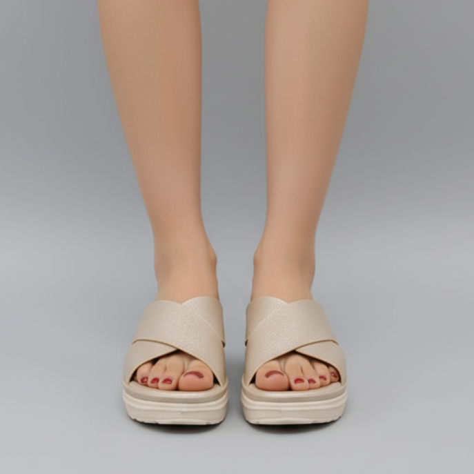 Beige sandals worn by a person on a gray background