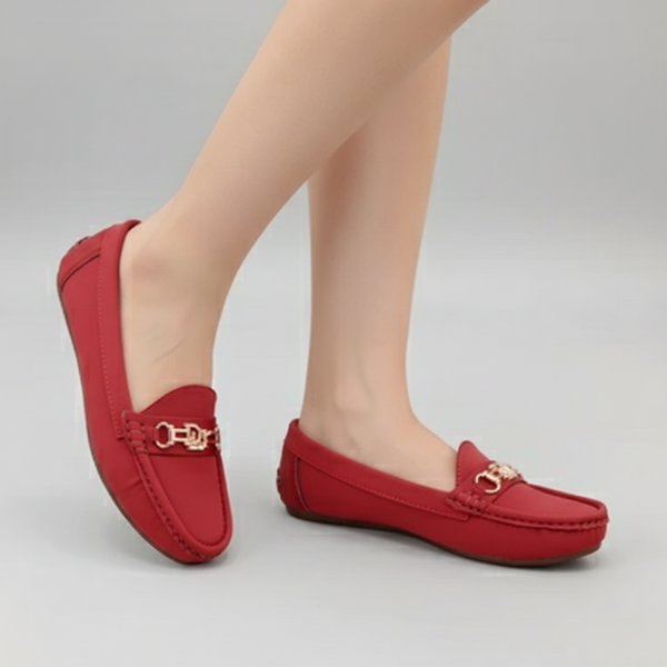Red loafers with gold accents worn by a person on a gray background