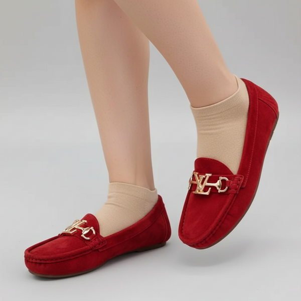 Red loafers with gold accents worn by a person on a gray background