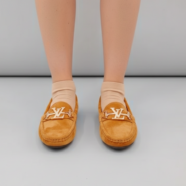 Brown loafers with a logo worn by a person on a gray background