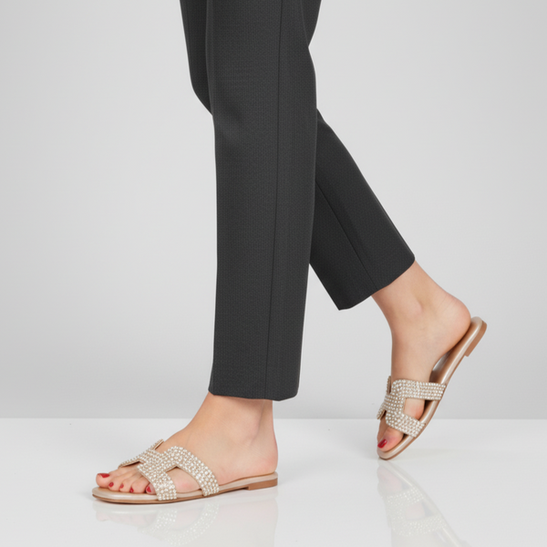 Person wearing sparkly sandals with black pants on a white background