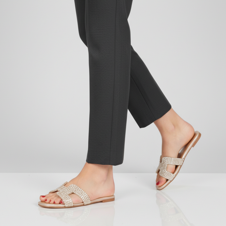 Person wearing sparkly sandals with black pants on a white background