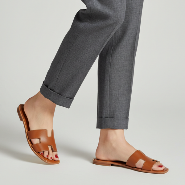 Brown sandals worn with gray pants on a light gray background