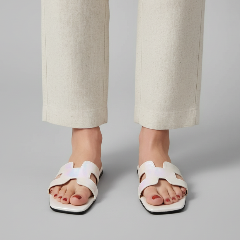 White sandals worn with beige pants on a gray background