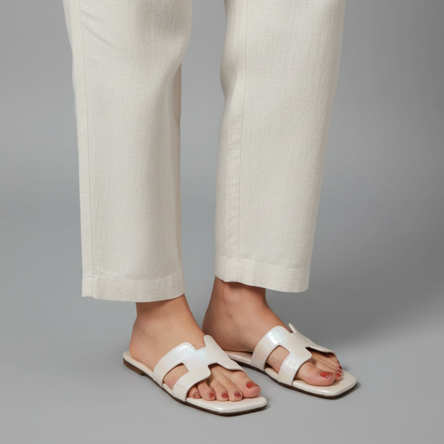 White sandals worn with light-colored pants on a gray background