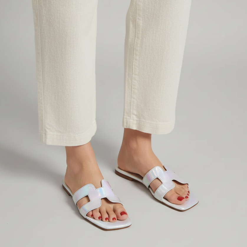White sandals worn with light-colored pants on a neutral background