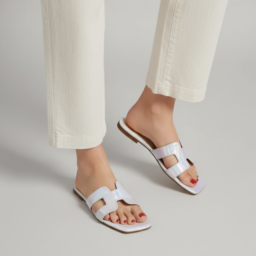White sandals worn with light-colored pants on a neutral background
