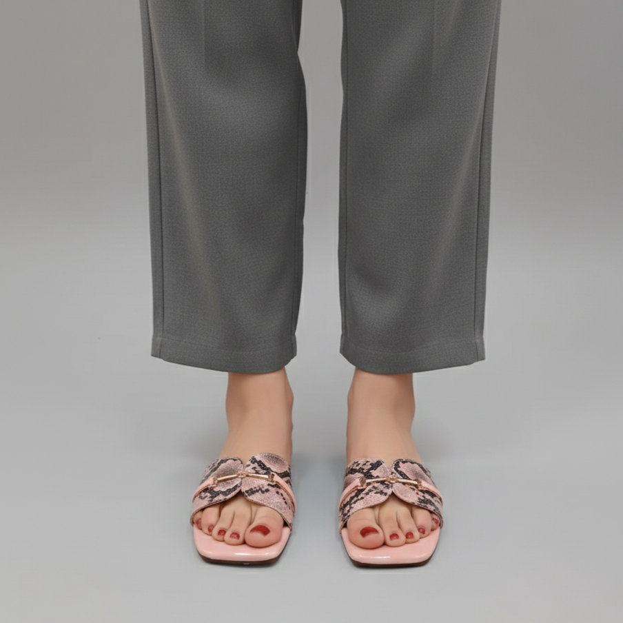 Person wearing pink sandals with snake print on a plain background