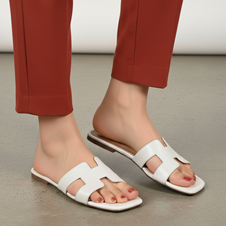 White sandals worn with red pants on a neutral background