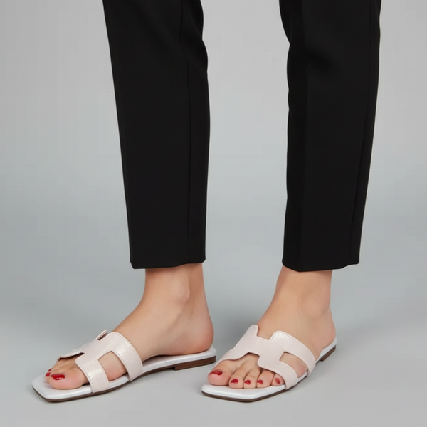 White sandals worn with black pants on a gray background