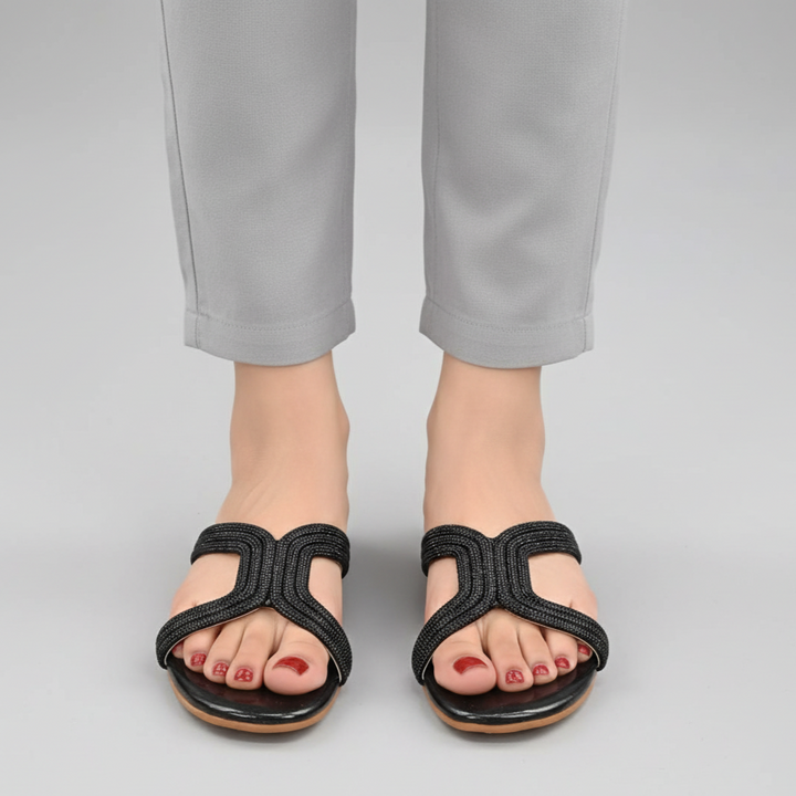 Black sandals worn with gray pants on a light gray background
