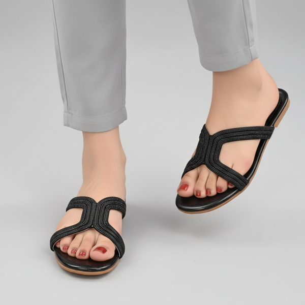 Black sandals worn with gray pants on a light gray background