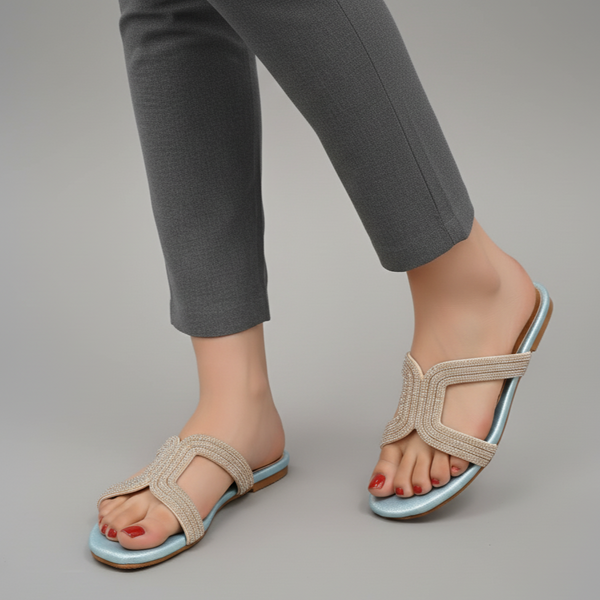 Beige sandals worn with gray pants on a neutral background