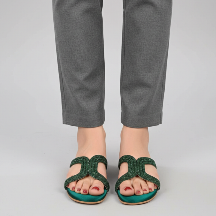 Green sandals worn with gray pants on a plain background