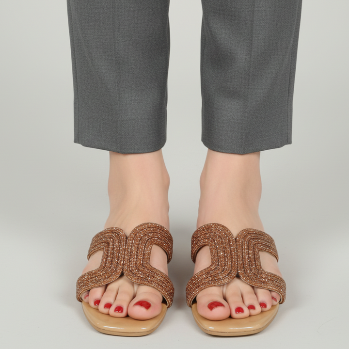 Brown sandals worn with gray pants on a plain background
