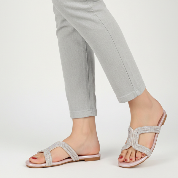 Silver sandals worn with light gray pants on a white background
