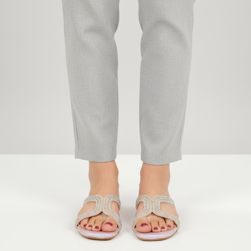 Person wearing light gray sandals and pants on a white background