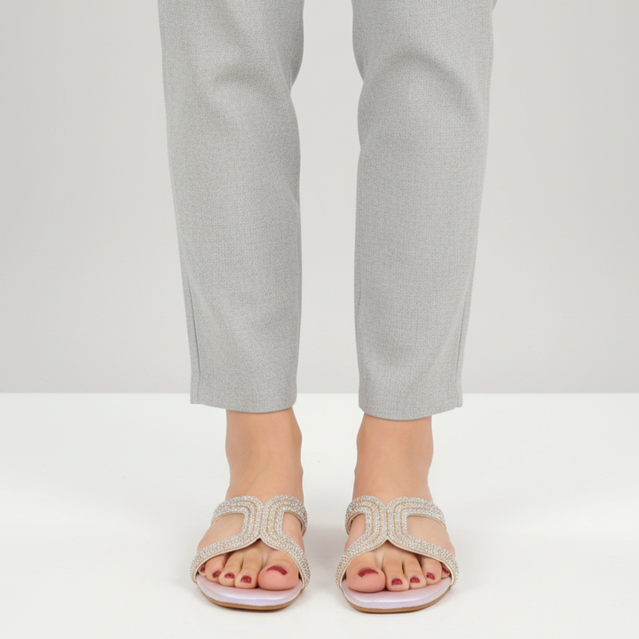 Person wearing light gray sandals and pants on a white background