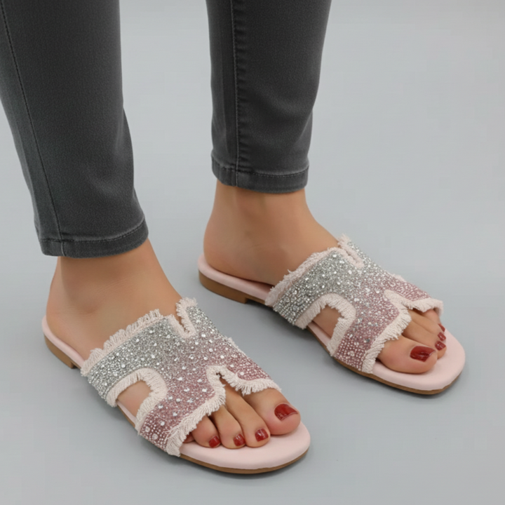 Sparkly sandals worn with black pants on a gray background