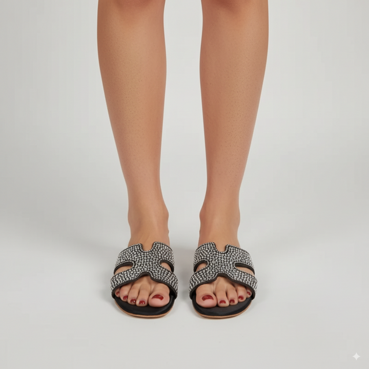 Black and white patterned sandals worn by a person on a plain background