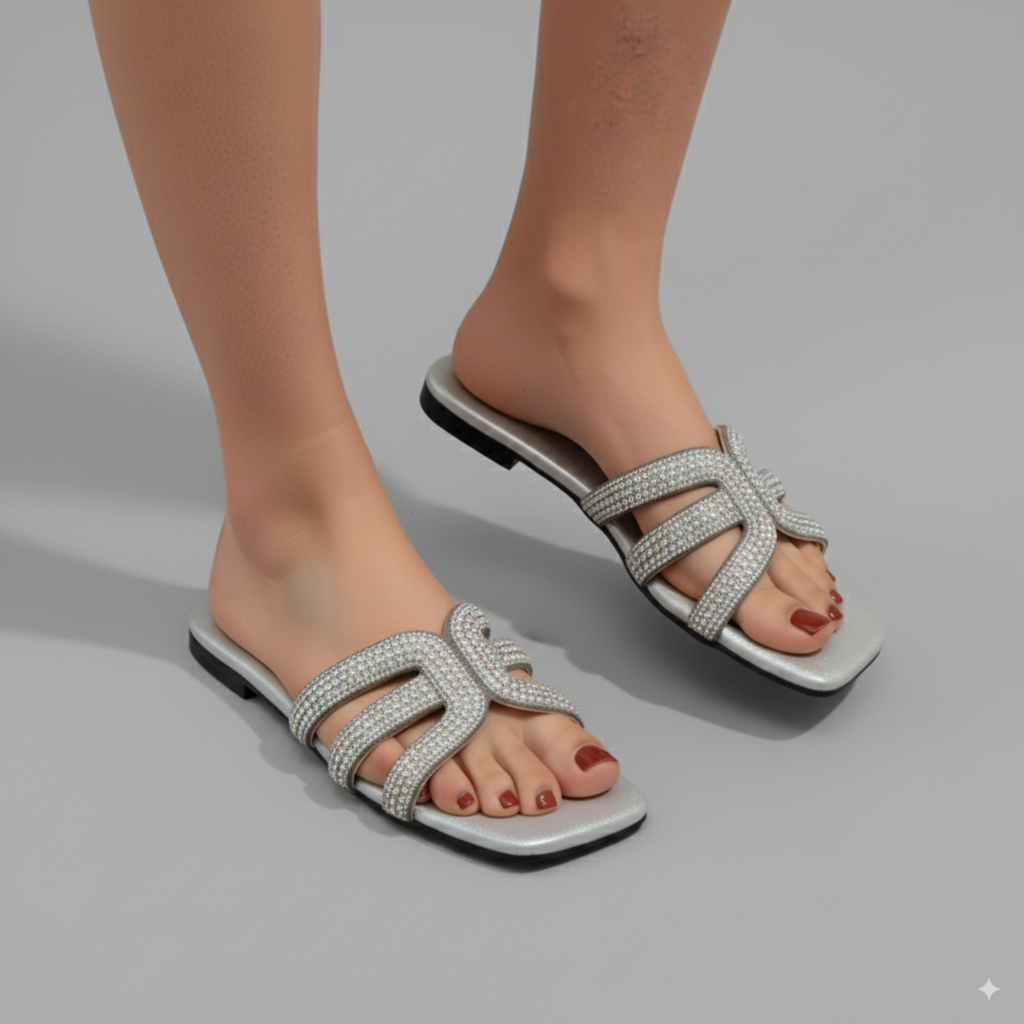 Silver sandals with a gray sole worn by a person on a gray background