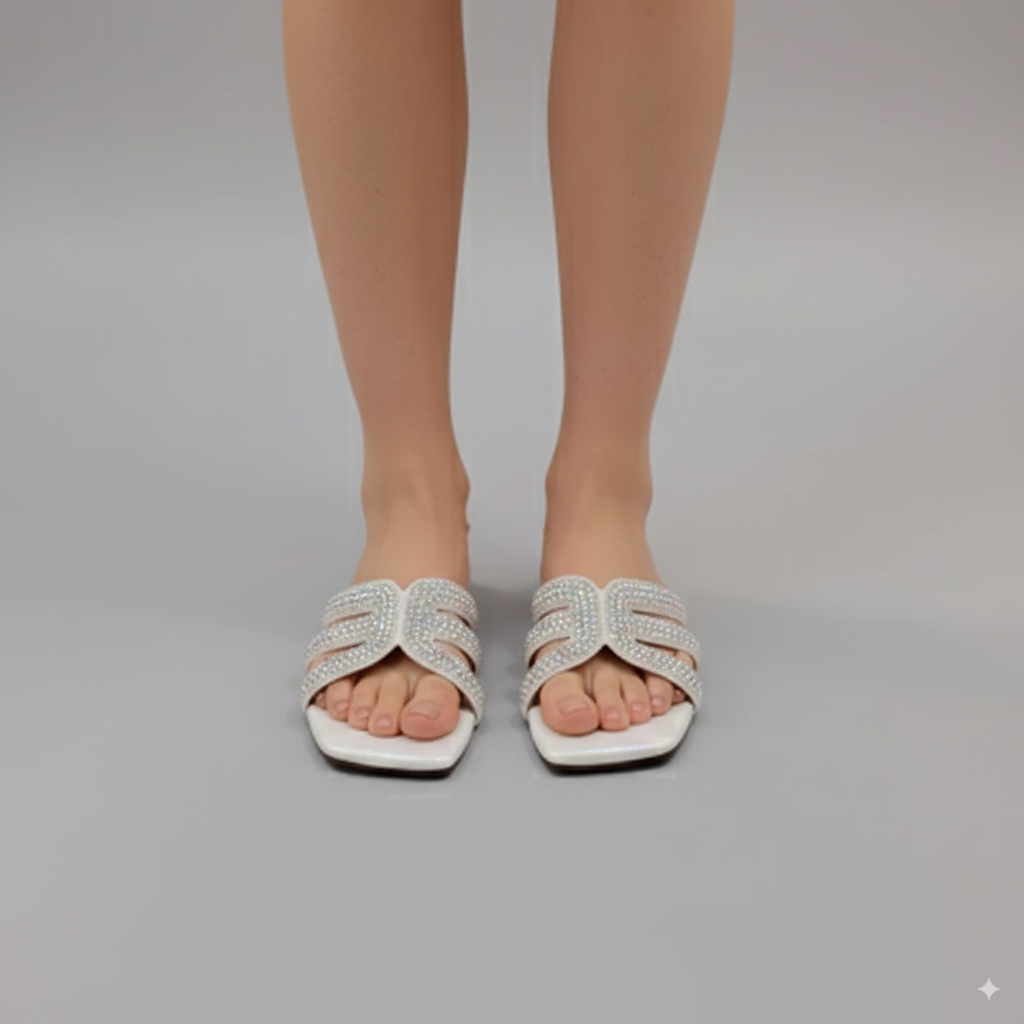 White sandals with decorative straps worn by a person on a gray background