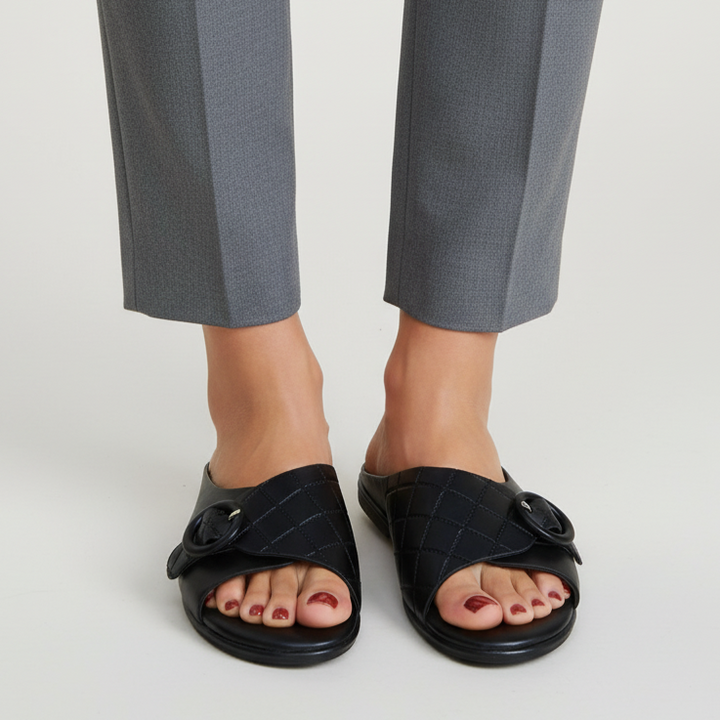 Black sandals worn with gray pants on a white background
