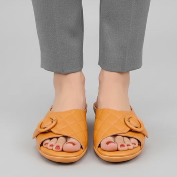 Person wearing mustard yellow sandals with decorative bows on a gray background