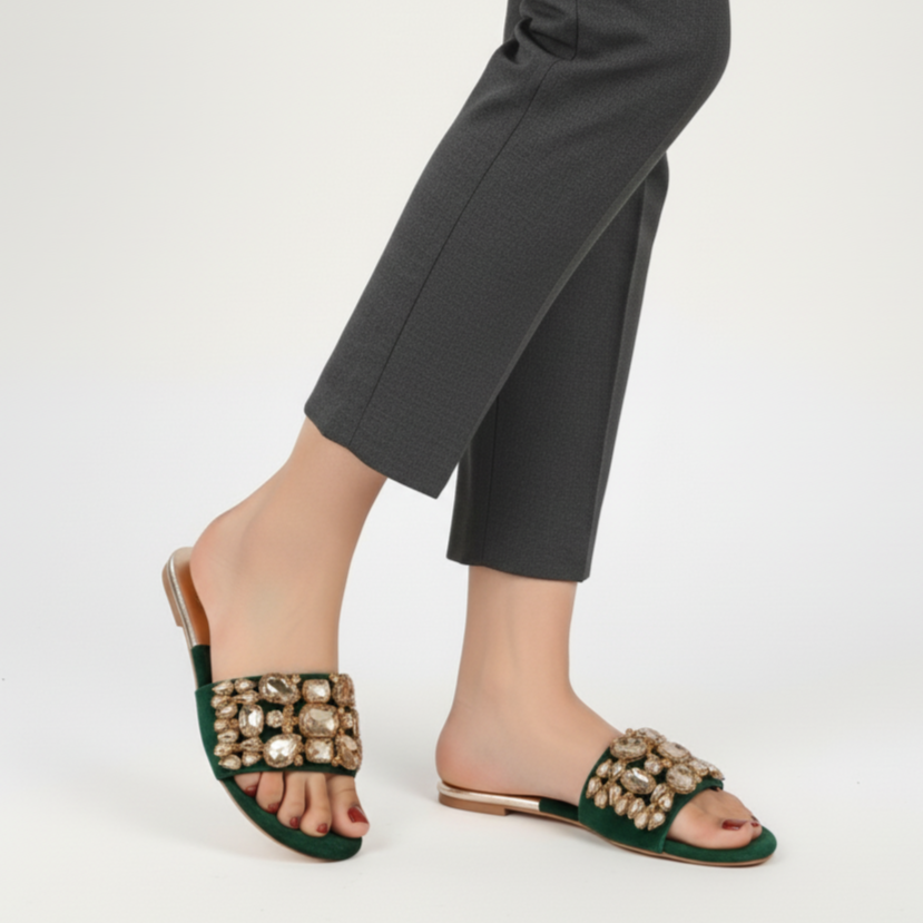 Green embellished sandals worn with gray pants on a white background