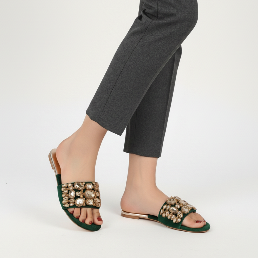 Green embellished sandals worn with gray pants on a white background