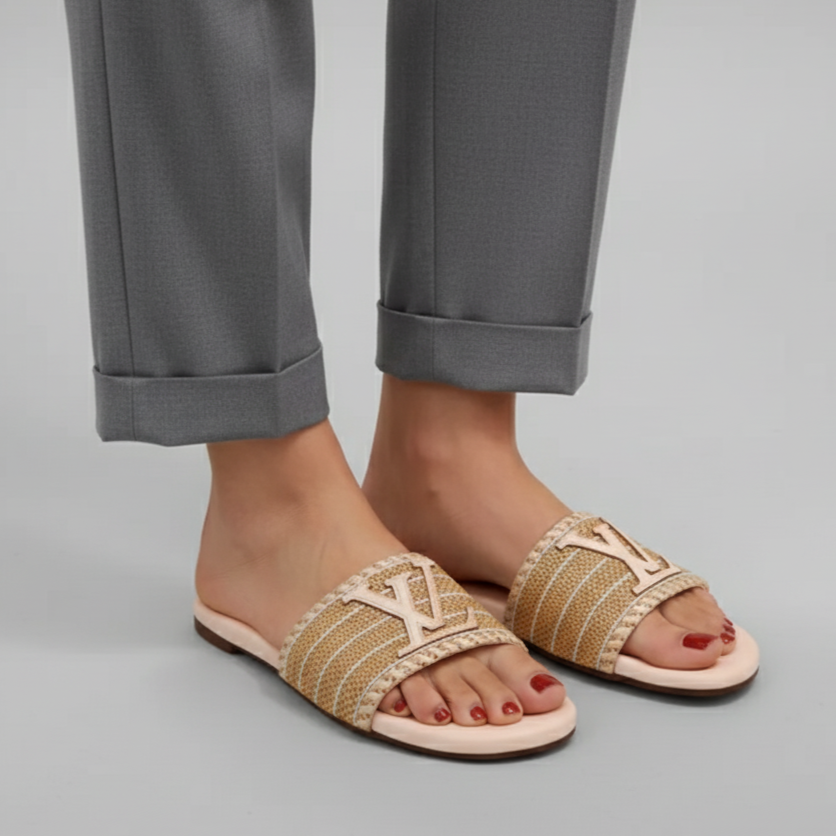 Beige sandals worn with rolled-up gray pants on a light gray background