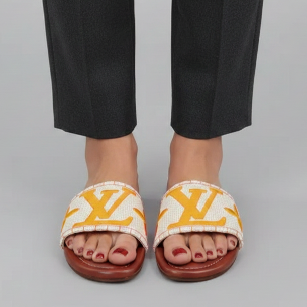 Person wearing black pants and white sandals with yellow logo on a gray background