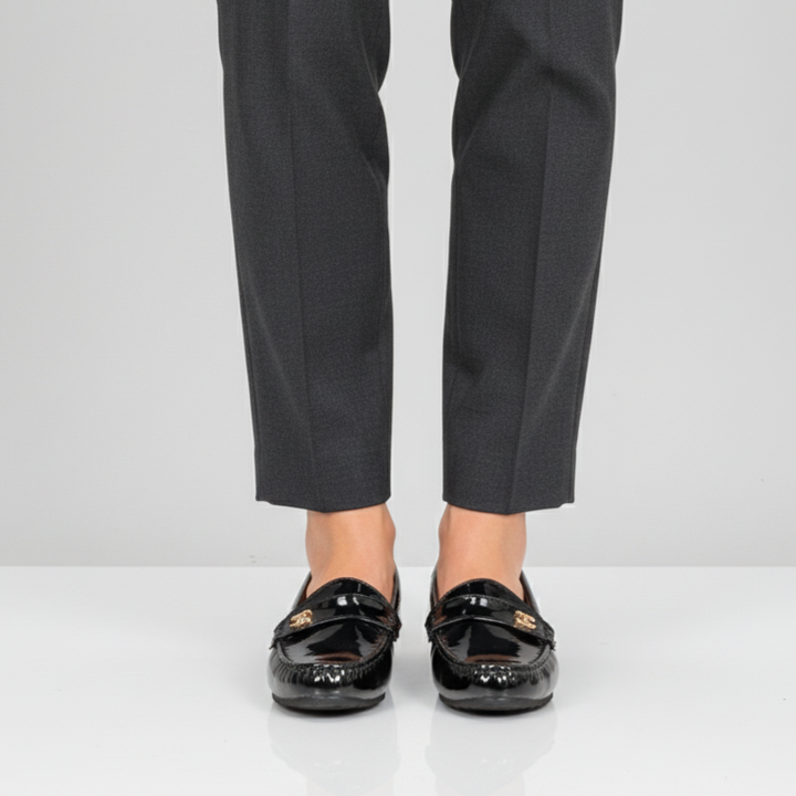 Person wearing black dress shoes and gray pants on a white background