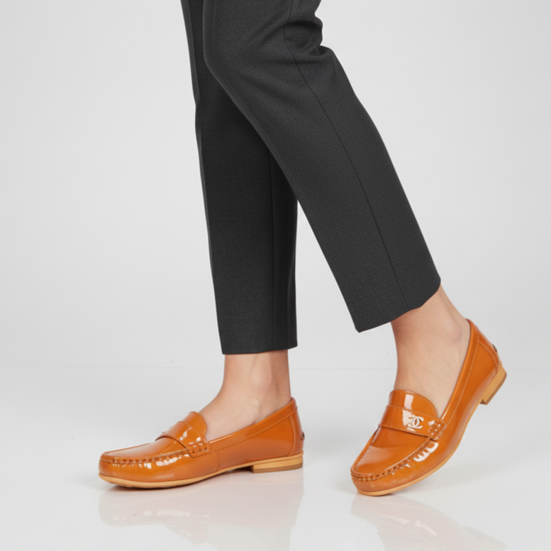 Person wearing black pants and orange loafers on a white background