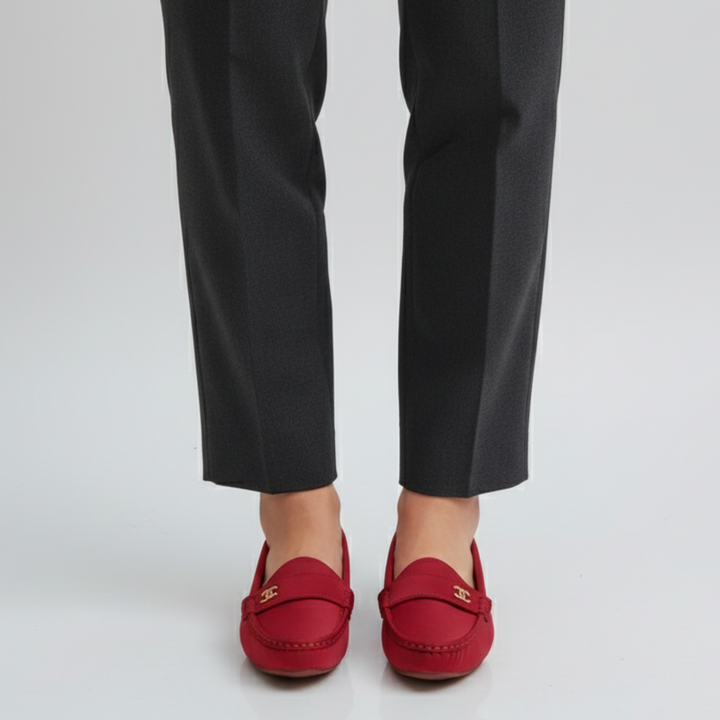 Red loafers worn with black pants on a white background