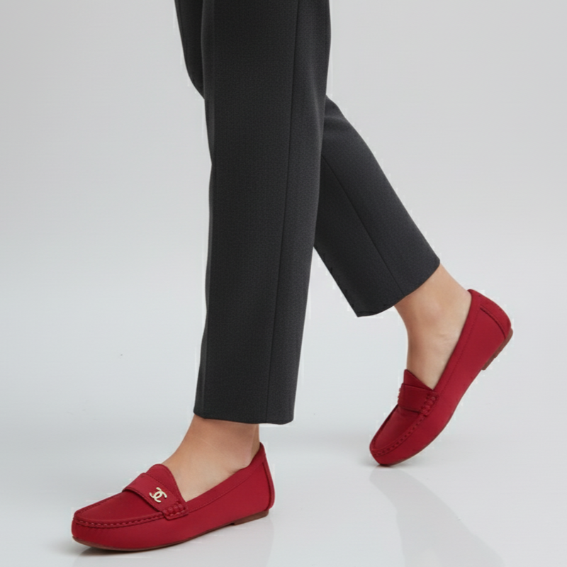 Red loafers worn with black pants on a light gray background