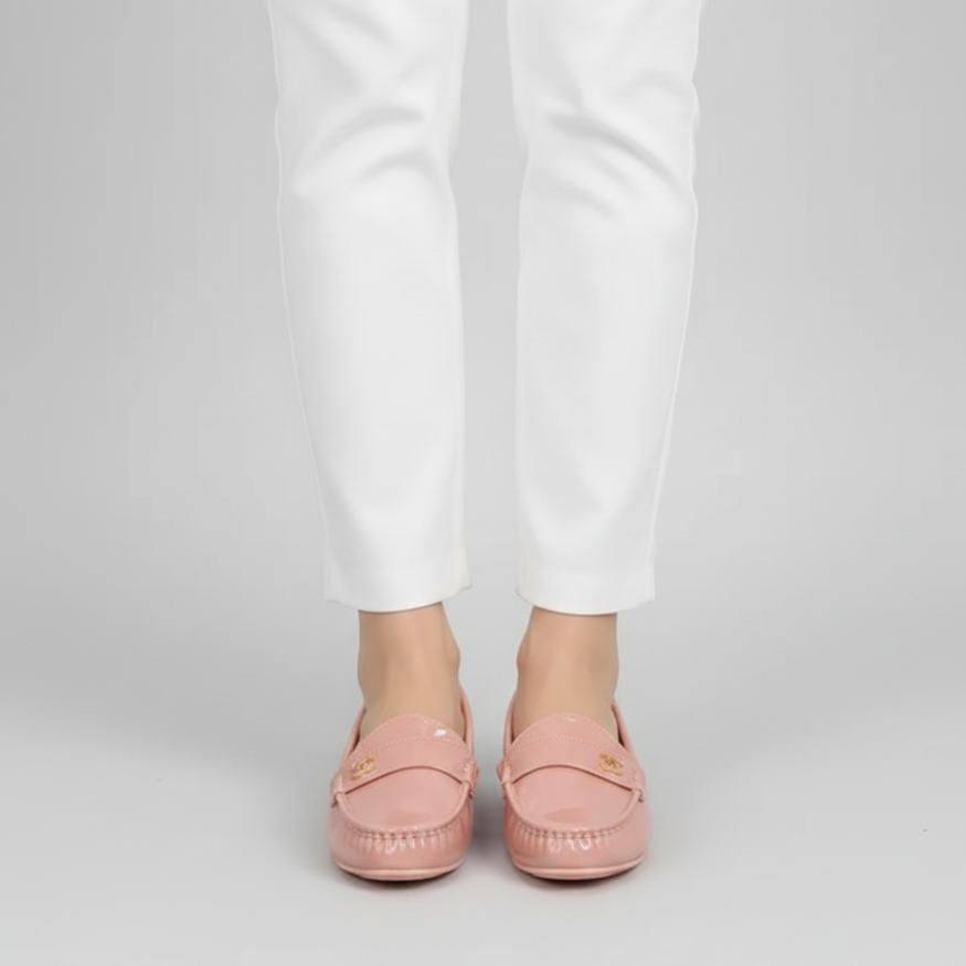 Person wearing pink loafers and white pants on a light gray background