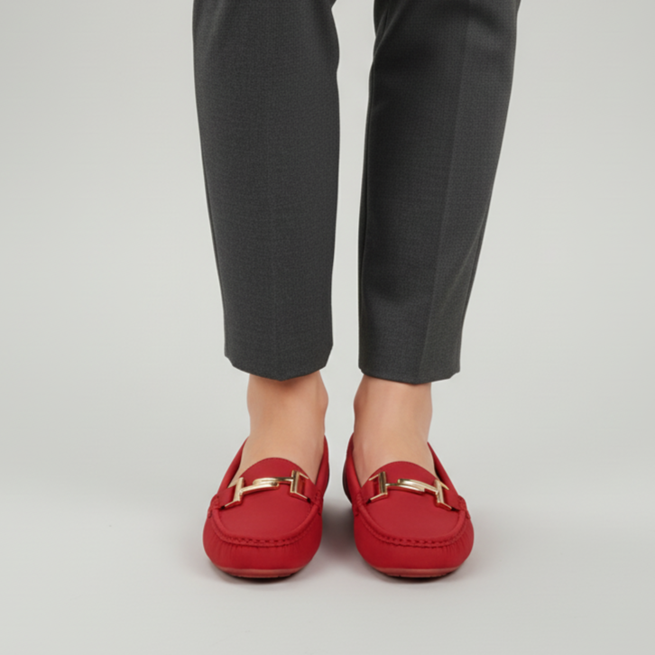 Red loafers worn with gray pants on a light gray background