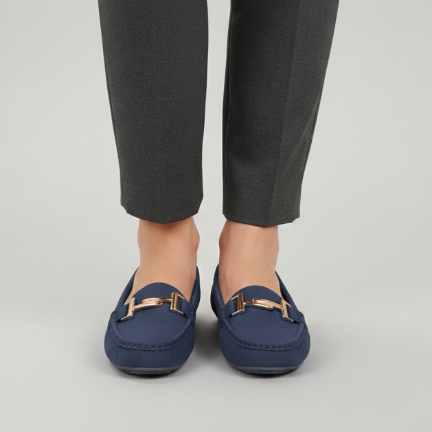 Person wearing navy loafers and gray pants on a light gray background