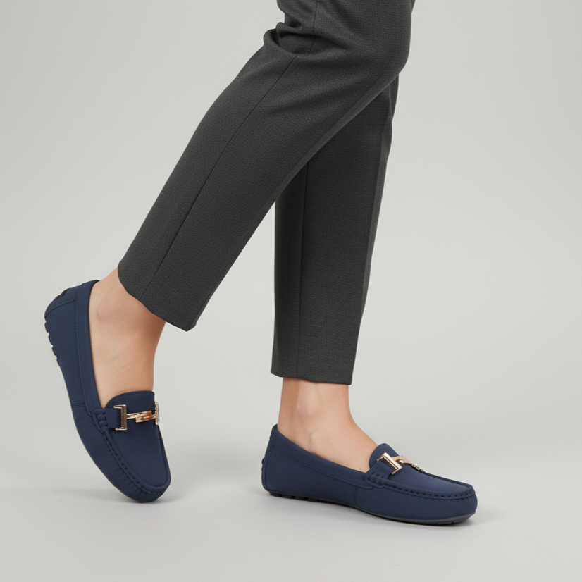 Navy loafers worn with dark gray pants on a light gray background