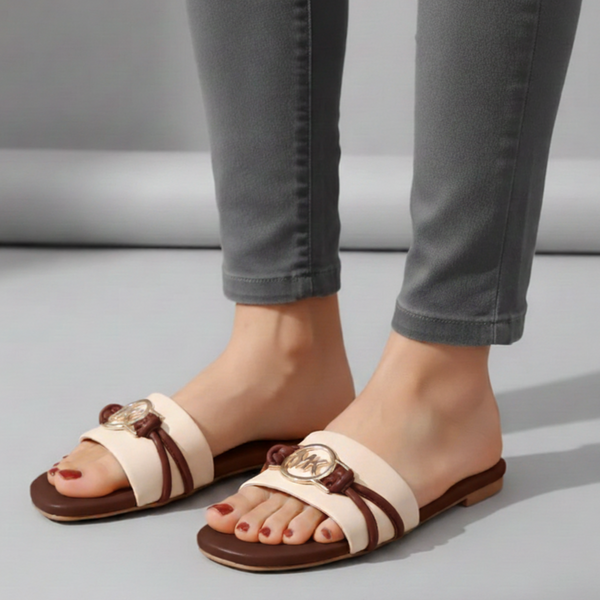 Beige and brown sandals worn with gray jeans on a neutral background