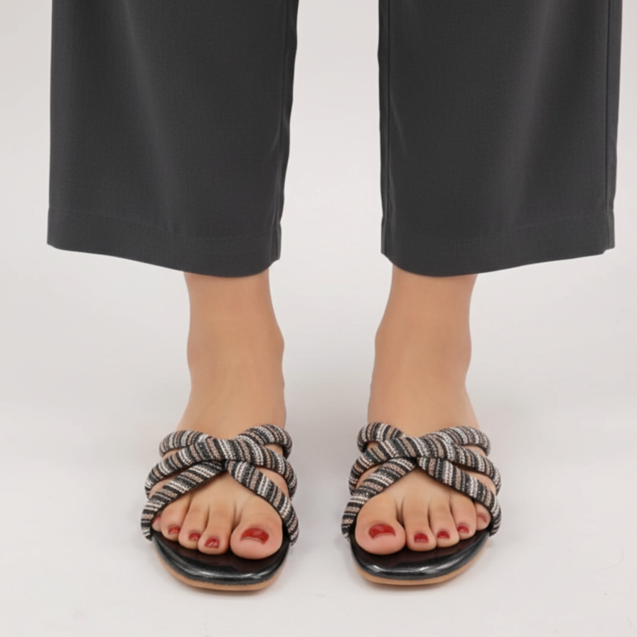 Black sandals with knotted straps worn with black pants on a white background