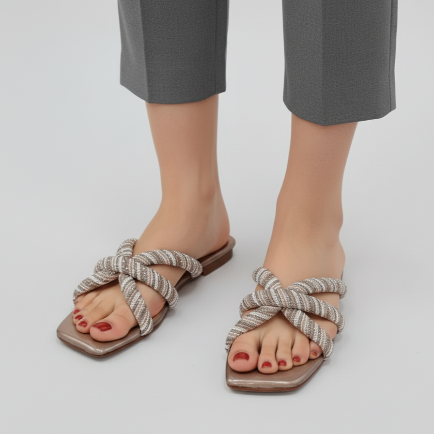 Pair of sandals with knotted straps worn by a person on a plain background