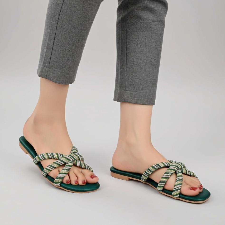 Green sandals worn with gray pants on a light gray background