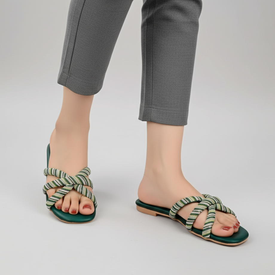 Green sandals with striped straps worn by a person on a plain background