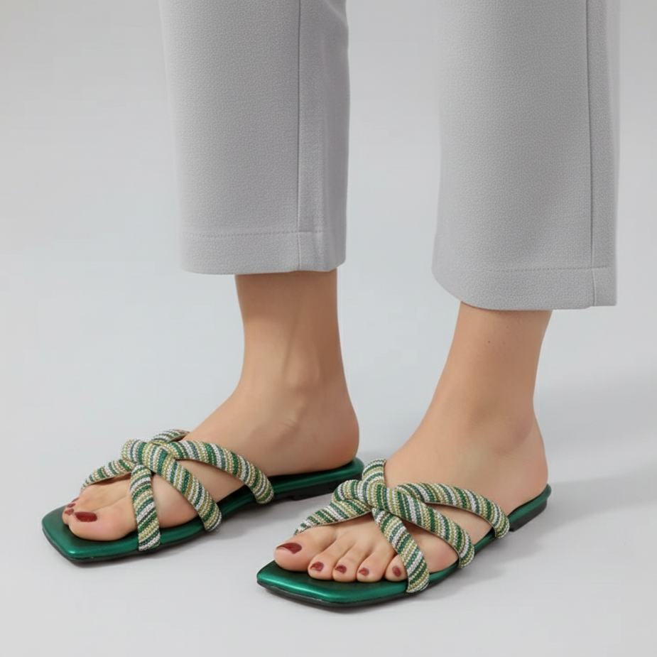 Green sandals with knotted straps worn by a person on a light gray background