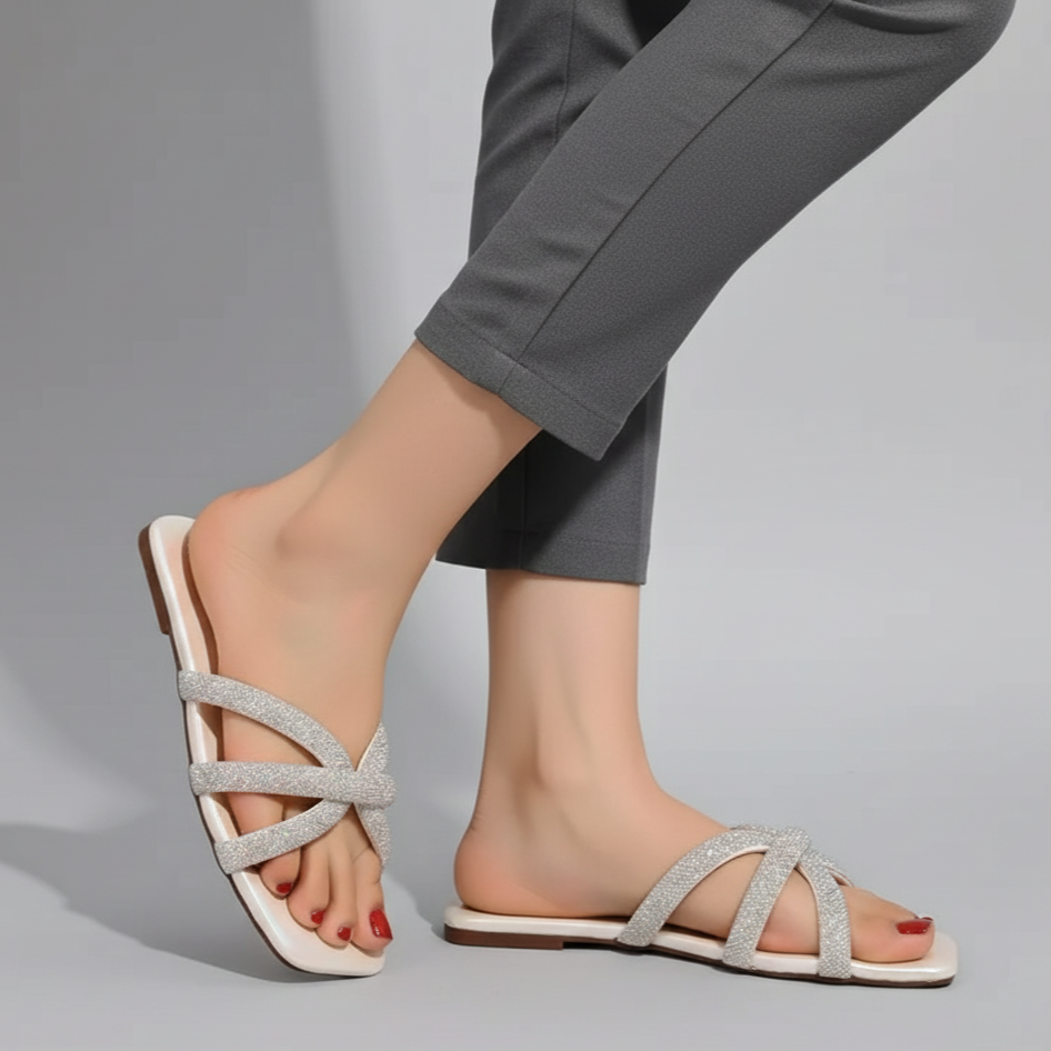 Silver strappy sandals worn with gray pants on a gray background