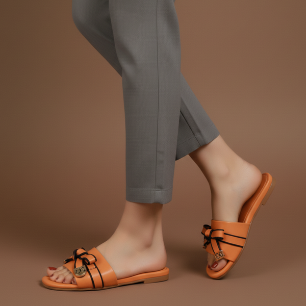 Person wearing orange sandals with black straps on a brown background