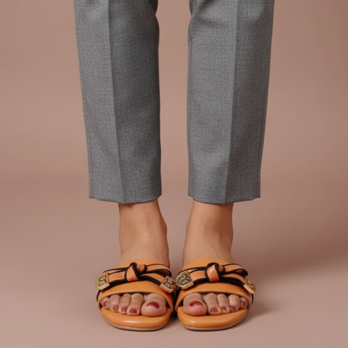 Person wearing gray pants and brown sandals on a beige background